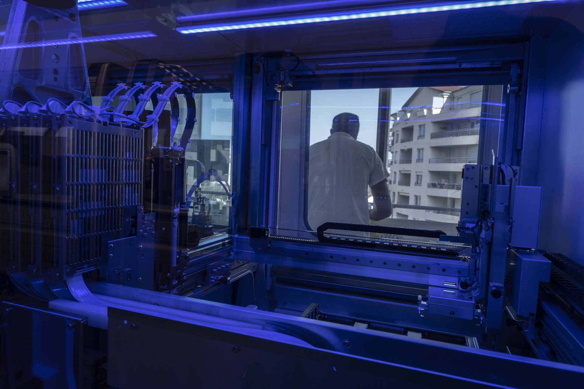 A lab technician at work, seen through the automated PCR system instrument